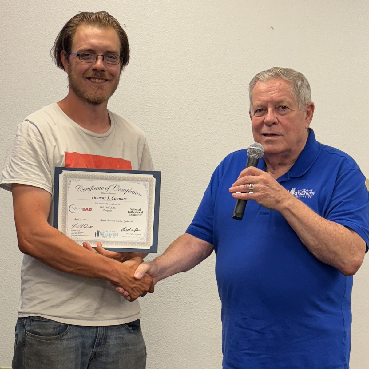 18 Spokane fathers graduate from 24-7 Dad® program: Another milestone in strengthening Spokane families 4 Father in light colored shirt with red stripe receiving certificate from instructor