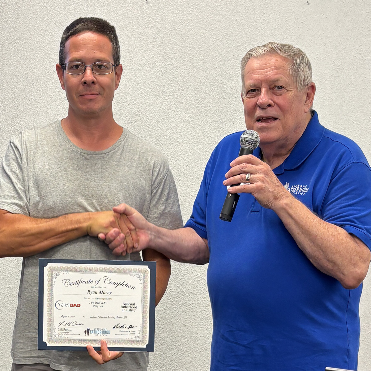 18 Spokane fathers graduate from 24-7 Dad® program: Another milestone in strengthening Spokane families 9 Father in gray shirt and glasses shaking hands with instructor while holding graduation certificate
