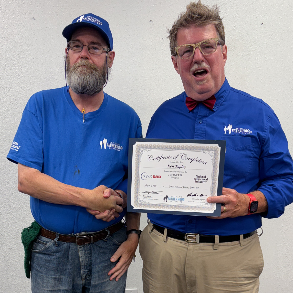 18 Spokane fathers graduate from 24-7 Dad® program: Another milestone in strengthening Spokane families 15 Bearded father in blue shirt and cap shaking hands with instructor while holding graduation certificate