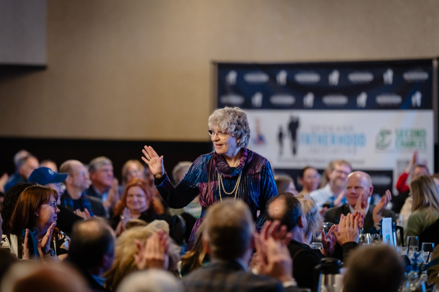 Becky Hauenstein stands and waves to a standing ovation from guests at the Spokane Fatherhood Initiative 10th anniversary celebration at Mirabeau Park Hotel.