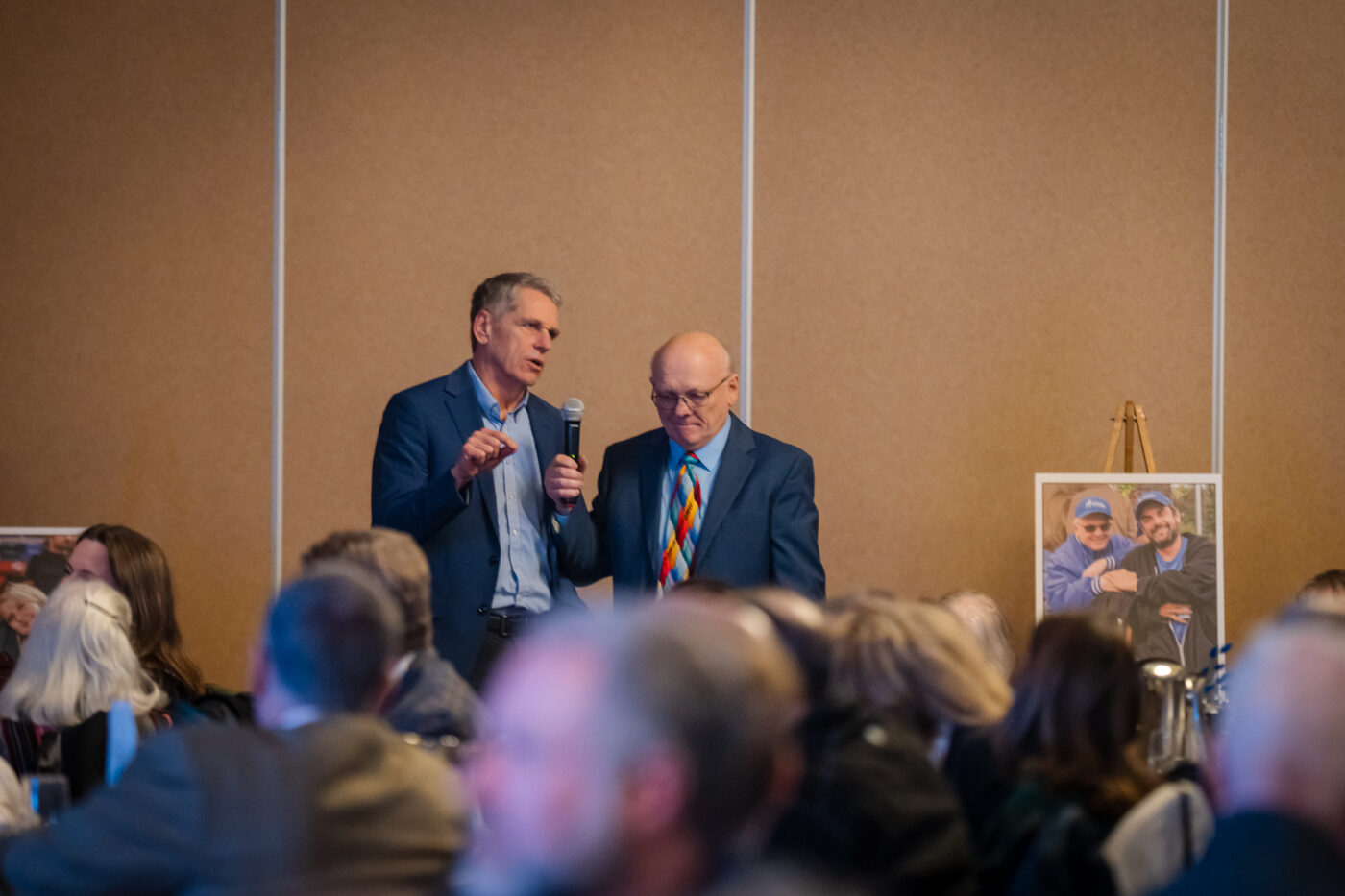 John Repsold stands and speaks into a microphone held by Ron Hauenstein at the SpoFI 10th anniversary celebration at Mirabeau Park Hotel.