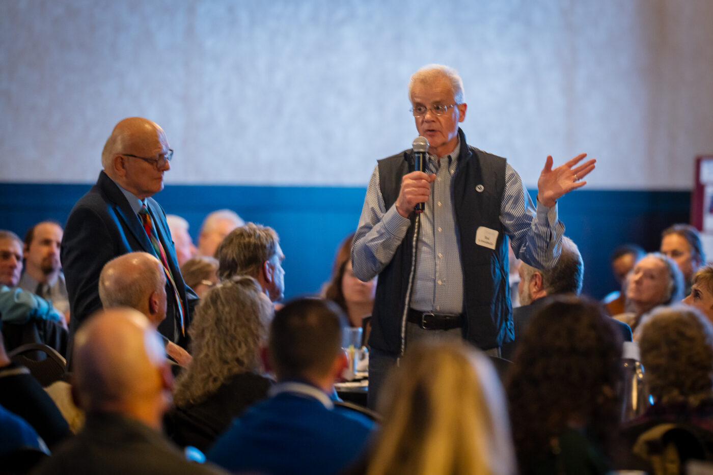 Rod Schneidmiller speaks into a microphone while Ron Hauenstein stands beside him at the SpoFI 10th anniversary celebration.