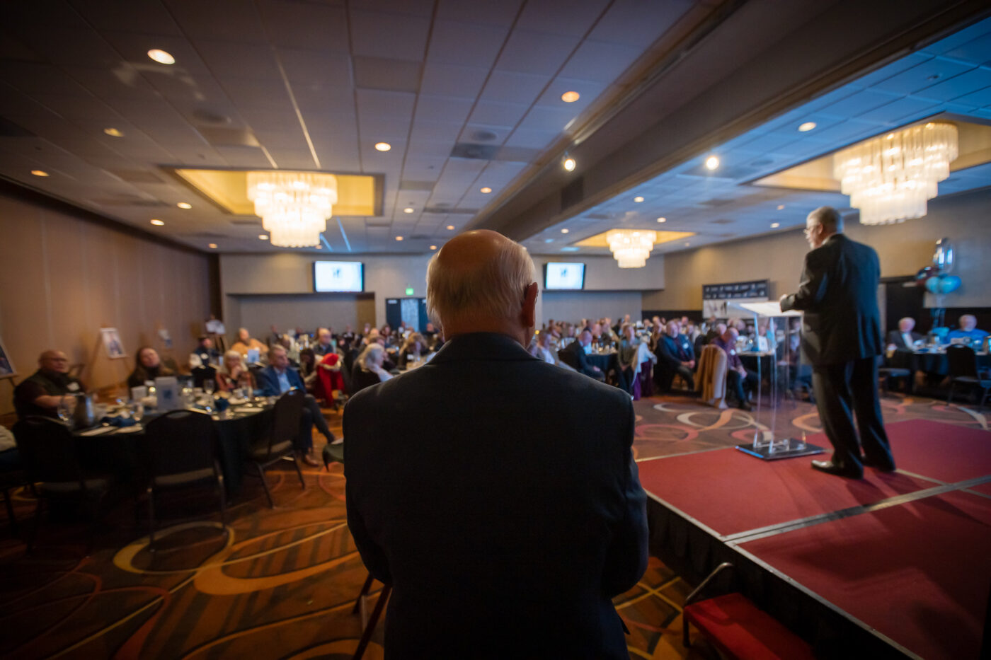 Mark Andresen delivers the closing prayer from the stage as guests listen in the Mirabeau Park Hotel ballroom during SpoFI’s 10-year celebration.