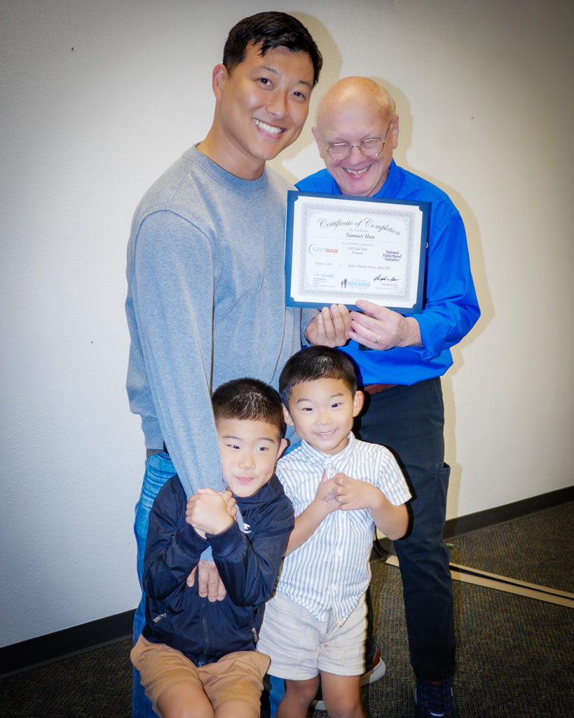 Graduate Samuel Han and his two sons beam with pride alongside instructor Ron Hauenstein