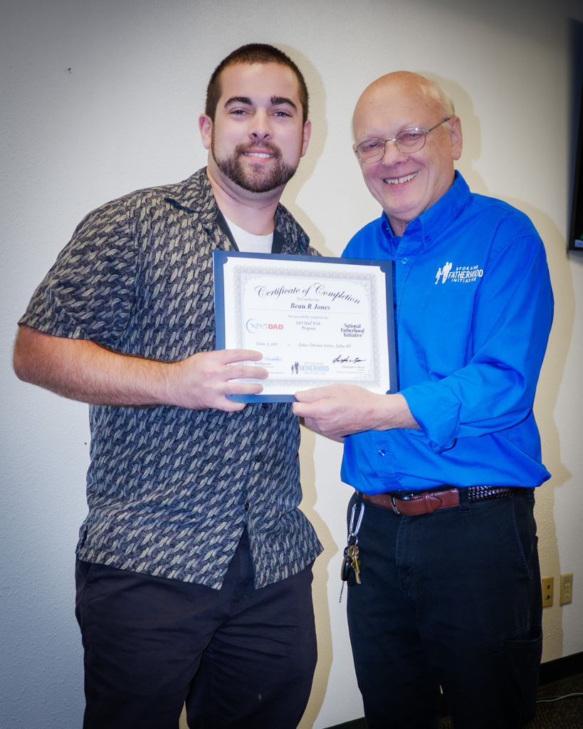 Graduate Beau Jones accepts his certificate and handshake from instructor Ron Hauenstein — one more dad finishing strong.