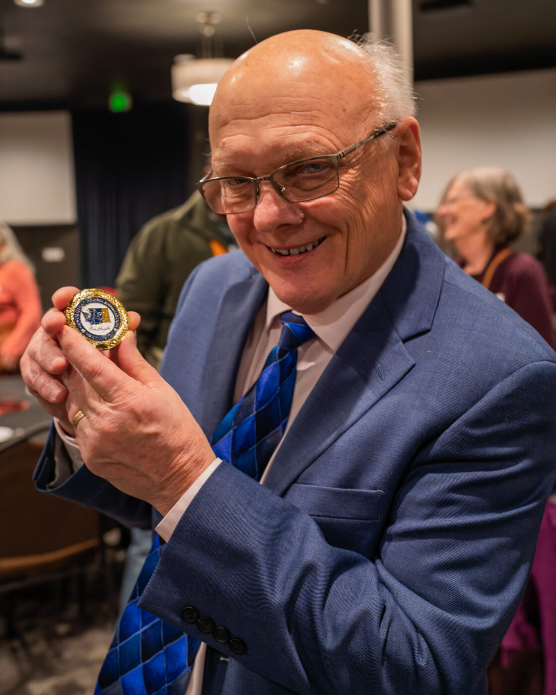 Building Legacy: Nearly 200 Gather to Celebrate Fatherhood and Family Transformation 5 Ron Hauenstein smiles while displaying commemorative challenge coin from Congressman Michael Baumgartner recognizing his leadership in fatherhood programming