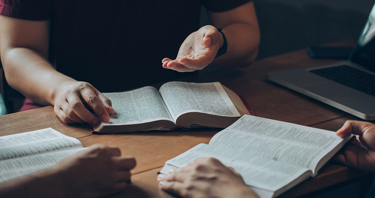 Men studying biblical manhood principles together at wooden table, open Bibles and discussion materials visible during SpoFI's Betterman course in Spokane