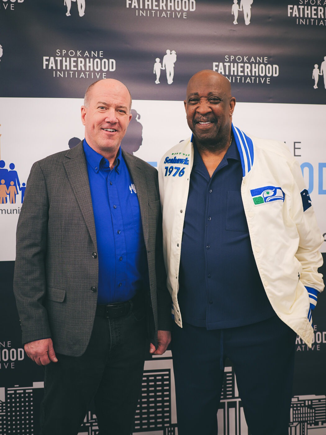 SpoFI's 100th 24-7 Dad class graduation recap: a night eight years in the making 25 Dave Sprunger, Operations and Programs Coordinator at Spokane Fatherhood Initiative, with Marvin Charles at the SpoFI 100th graduation step-and-repeat backdrop, April 10, 2026