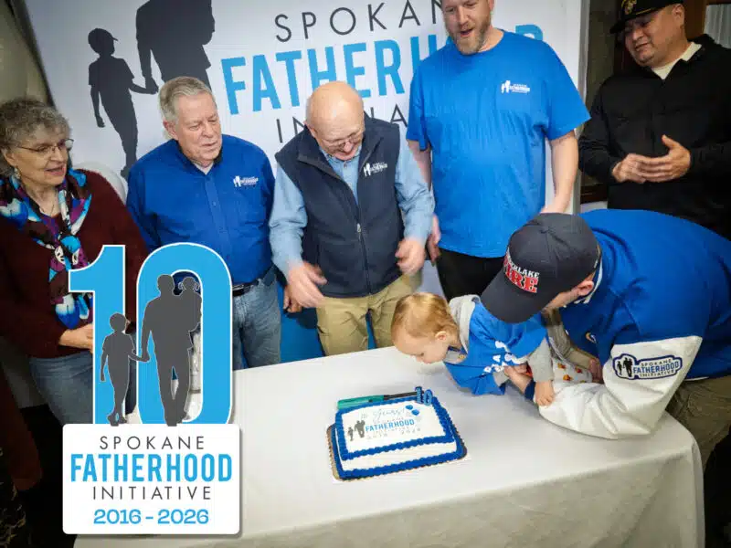 Child blowing out candle at Spokane Fatherhood Initiative 10th birthday celebration with SpoFI founder and leadership watching January 2026