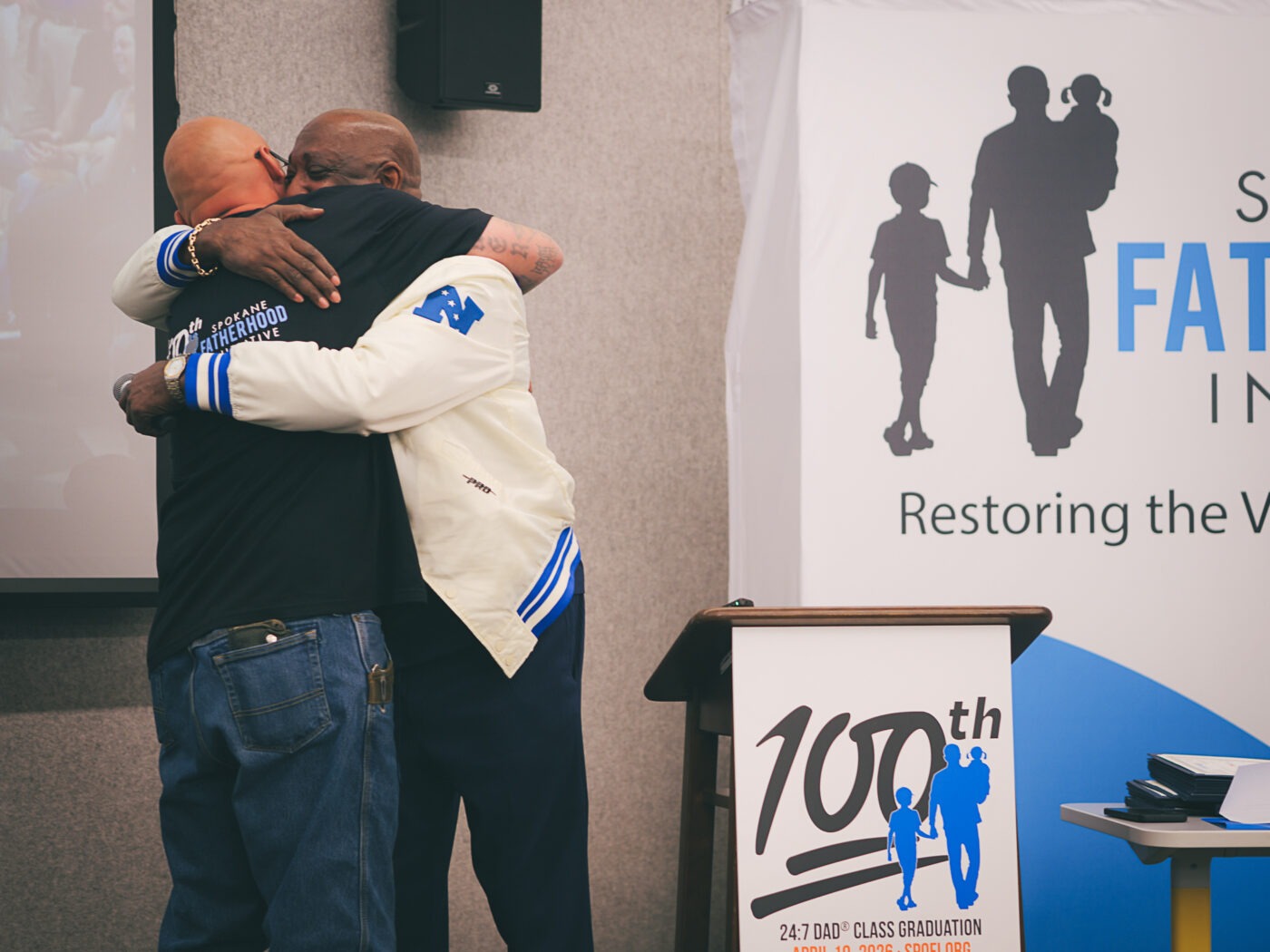 SpoFI's 100th 24-7 Dad class graduation recap: a night eight years in the making 6 Marvin Charles and Matt White embrace on stage at SpoFI's 100th 24-7 Dad graduation at The Hive in Spokane, April 10, 2026