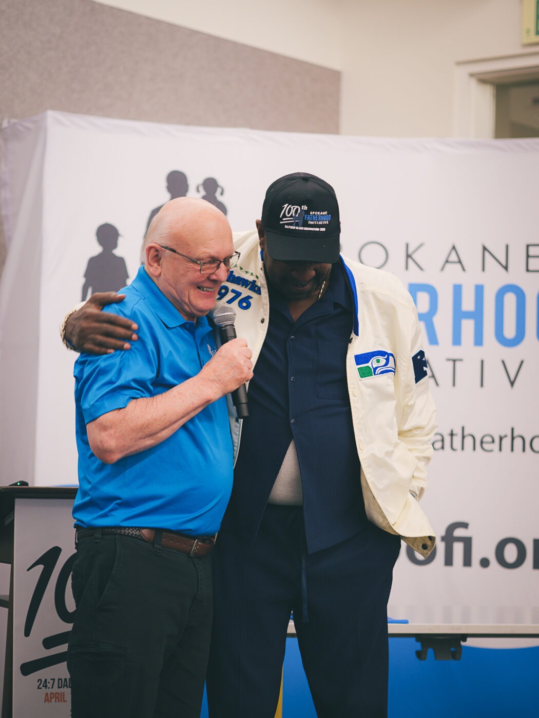 SpoFI's 100th 24-7 Dad class graduation recap: a night eight years in the making 8 Ron Hauenstein and Marvin Charles share a lighthearted moment on stage at SpoFI's 100th graduation; Marvin wears the commemorative SpoFI 100th graduation cap