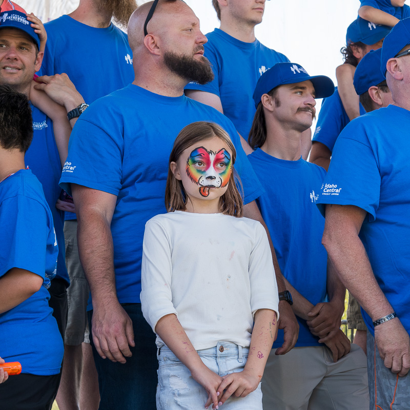 Community connection strengthens Spokane families at Father's Day celebration 11 Alt text:
"Group of SpoFI fathers in blue shirts gather on stage with young girl with colorful dog face paint, awaiting announcement of 2025 Father of the Year winners at Spokane Father's Day celebration